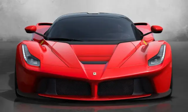 Przód czerwonego LaFerrari z czarnym dachem i przyciemnianymi szybami, błyszczący na tle szarej ściany.