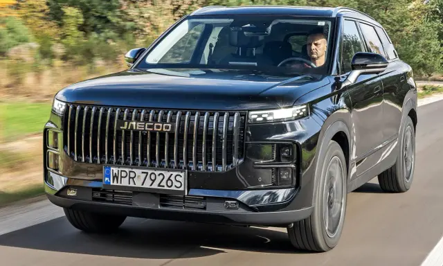 Czarny Jaecoo 7 w ruchu, z kierowcą za kierownicą. Sprawdź aktualną jaecoo 7 cena i dowiedz się więcej o tym SUV-ie.