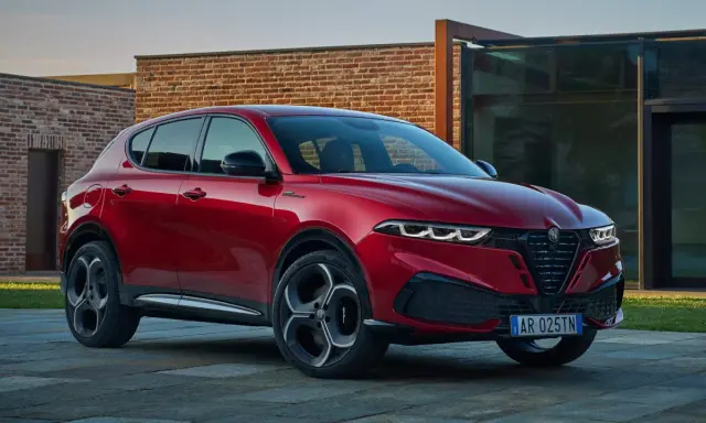 Czerwone Alfa Romeo Tonale na tle nowoczesnej architektury. Sprawdź aktualną alfa romeo tonale cena i konfigurację.