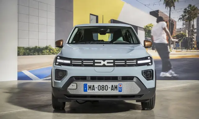 Jasnoszary dacia elektryk z miedzianymi lusterkami. Z przodu logo Dacia i tablica rejestracyjna MA-080-AM 92.