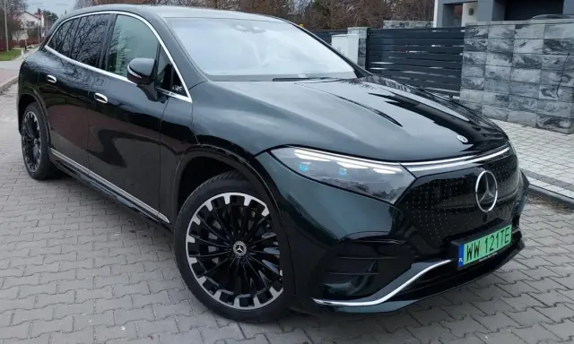 Elegancki, ciemnozielony Mercedes EQS SUV z nowoczesnymi światłami i felgami stoi na podjeździe.
