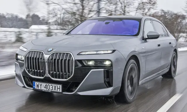 Szare BMW Serii 7 w ruchu, z widocznym grillem i światłami. Sprawdź aktualną bmw 7 cena.