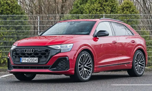 Czerwony Audi RS Q8 z czarnymi felgami stoi na parkingu.