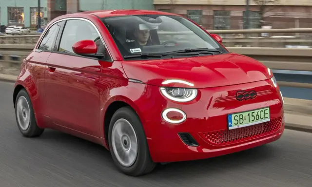 Czerwony Fiat 500 jedzie po drodze. Sprawdź aktualną fiat 500 cena i dowiedz się więcej o tym stylowym samochodzie.
