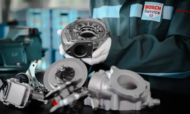 Mechanik w rękawiczkach prezentuje części turbosprężarki p0299. W tle logo Bosch Service.