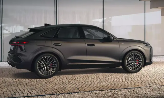 Elegancki Audi Q3 2025 w ciemnym kolorze, z dynamiczną linią nadwozia, prezentuje się na tle nowoczesnej architektury.