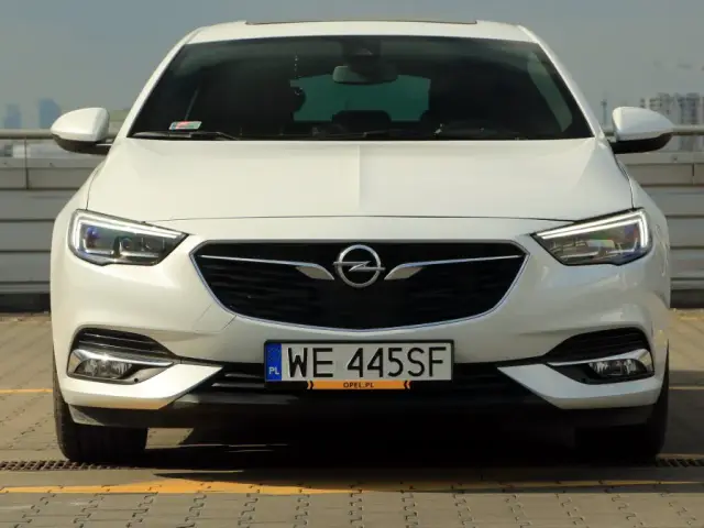 Biały Opel Insignia 2.0 Turbo z polskimi tablicami WE 445SF zaparkowany na dachu.