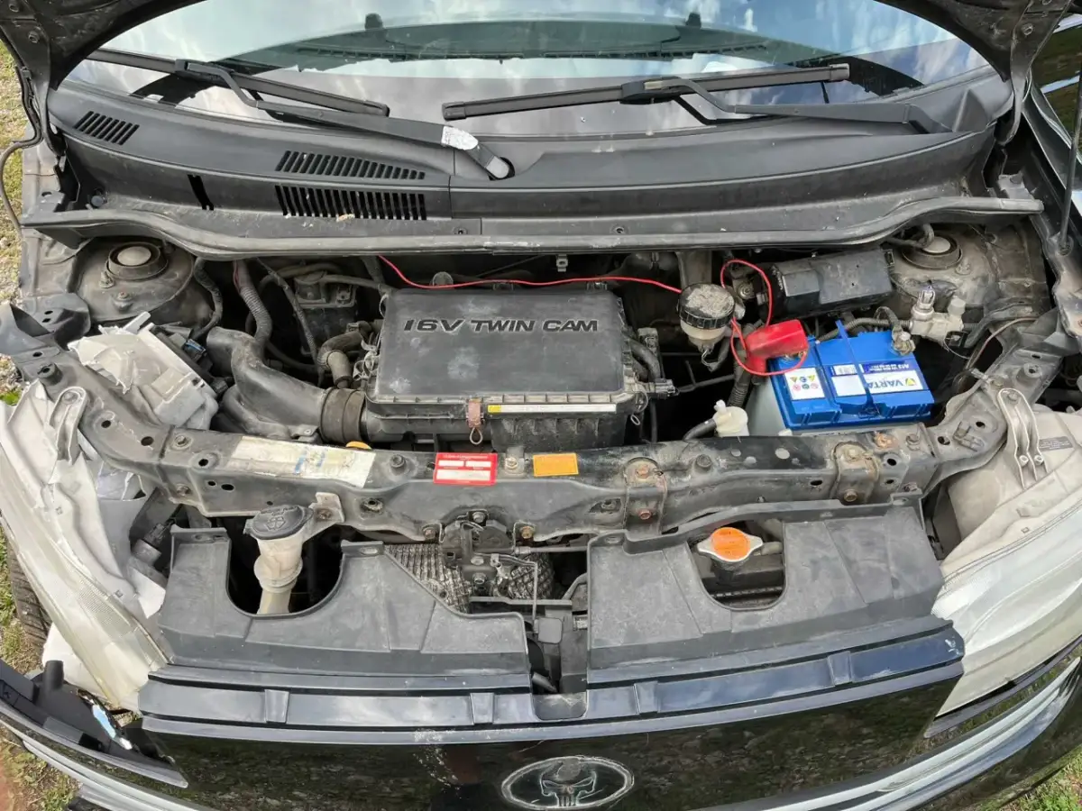Silnik 1.6 VVT-i w Daihatsu Materia, z widocznym akumulatorem Varta i elementami układu chłodzenia.