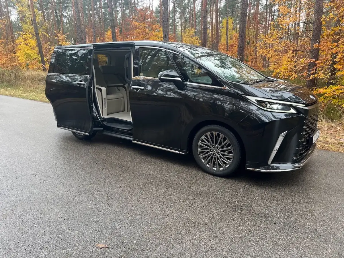 Elegancki Lexus LM 350h z otwartymi drzwiami, zapraszający do luksusowego wnętrza, na tle jesiennego lasu.