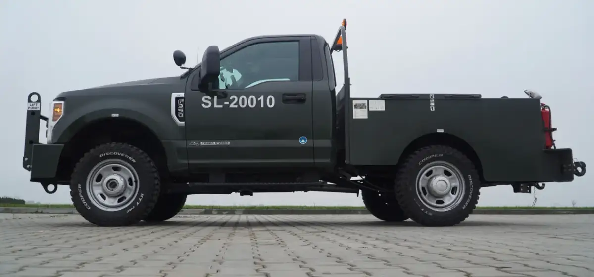 Ciemnozielony Ford F350 z zabudową serwisową, numerem SL-20010 i oponami Cooper Discoverer STT Pro.