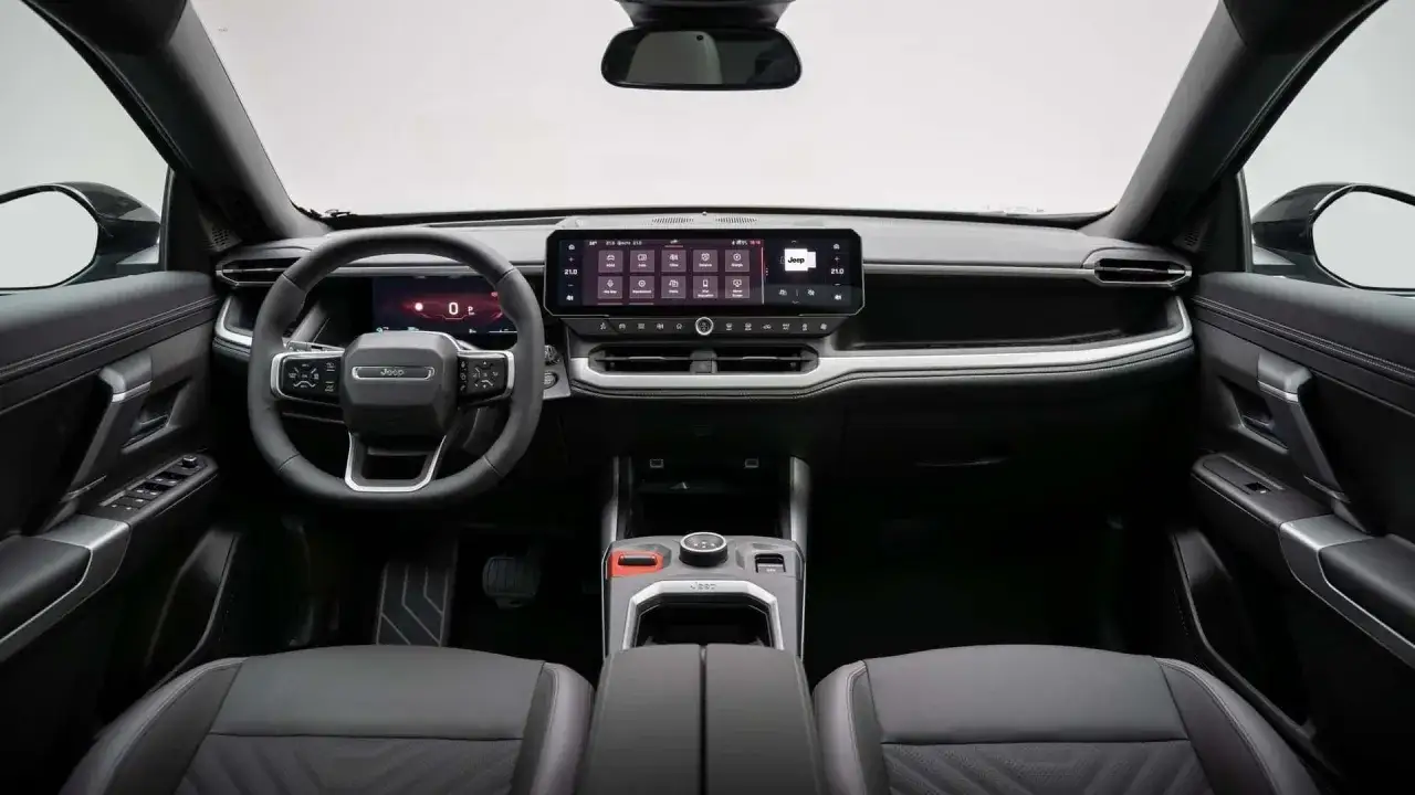 Wnętrze Jeep Compass 2025: nowoczesny kokpit z dużym ekranem dotykowym, cyfrowymi zegarami i skórzaną kierownicą.