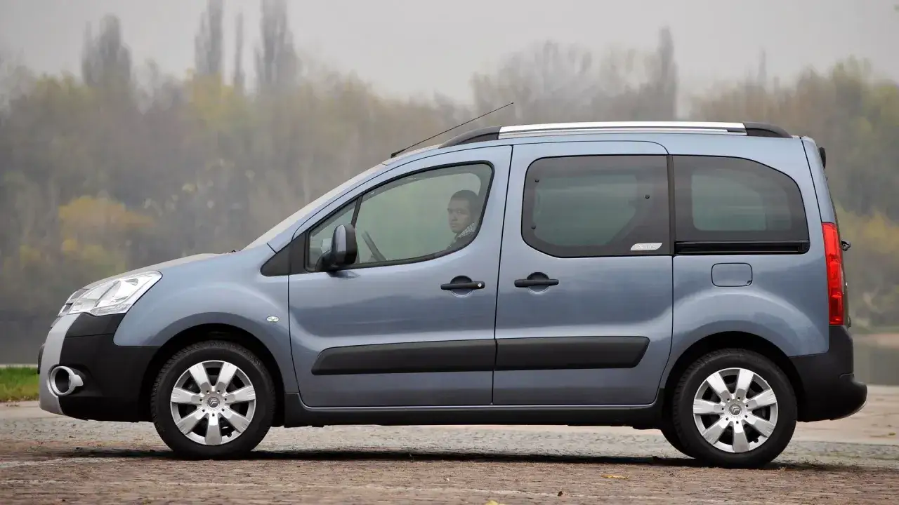 Błękitny Citroen Berlingo 1.6 HDI z młodym kierowcą za kierownicą, zaparkowany na tle mglistego krajobrazu.
