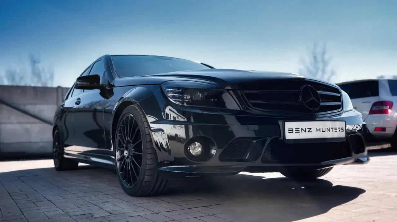 Czarny Mercedes C63 AMG W204 z przyciemnionymi światłami i felgami, gotowy do polowania na wrażenia.