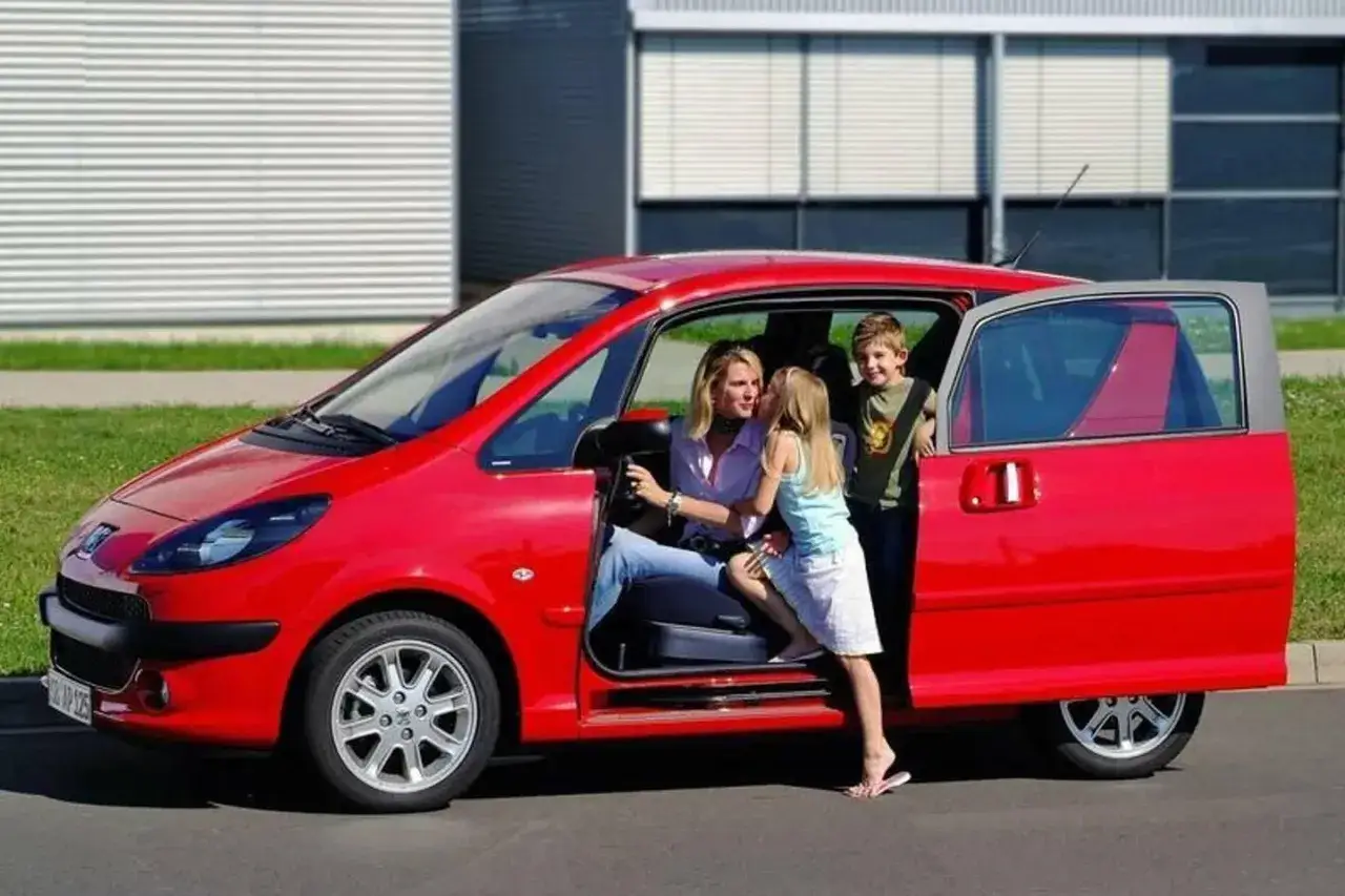 Czerwony Peugeot 1007 z otwieranymi drzwiami, matka z dwójką dzieci.
