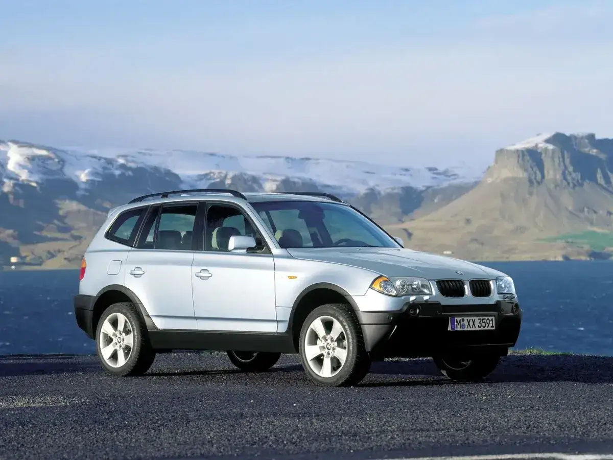 Srebrne BMW X3 E83 na tle gór i morza. Idealne na wyprawę w nieznane.