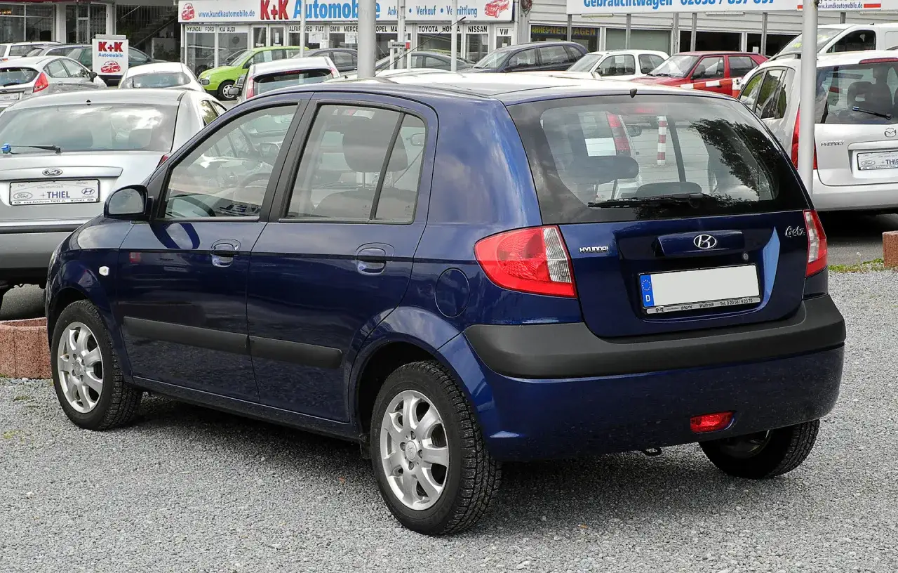 Ciemnoniebieski Hyundai Getz 1.1 stoi na placu z innymi samochodami.