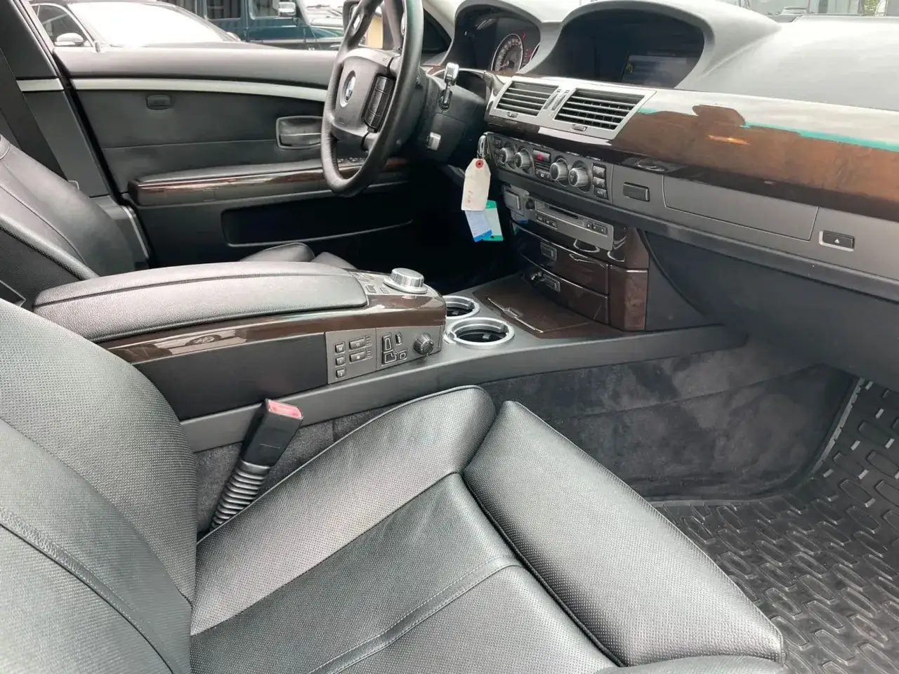 Wnętrze BMW 750i: czarna skórzana tapicerka, drewniane wykończenia, kierownica i konsola środkowa.
