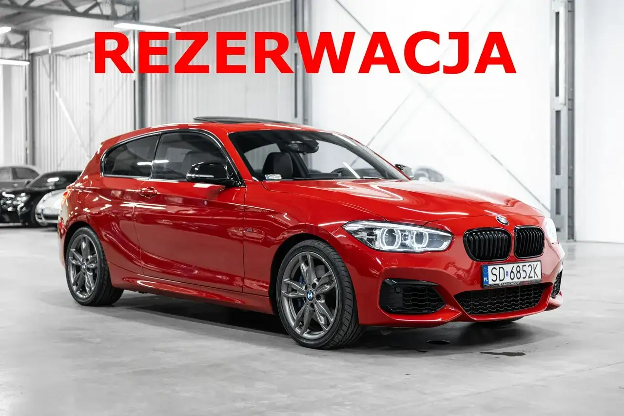 Czerwone BMW 140i w wersji hatchback, z czarnymi dodatkami i felgami, stoi w garażu.