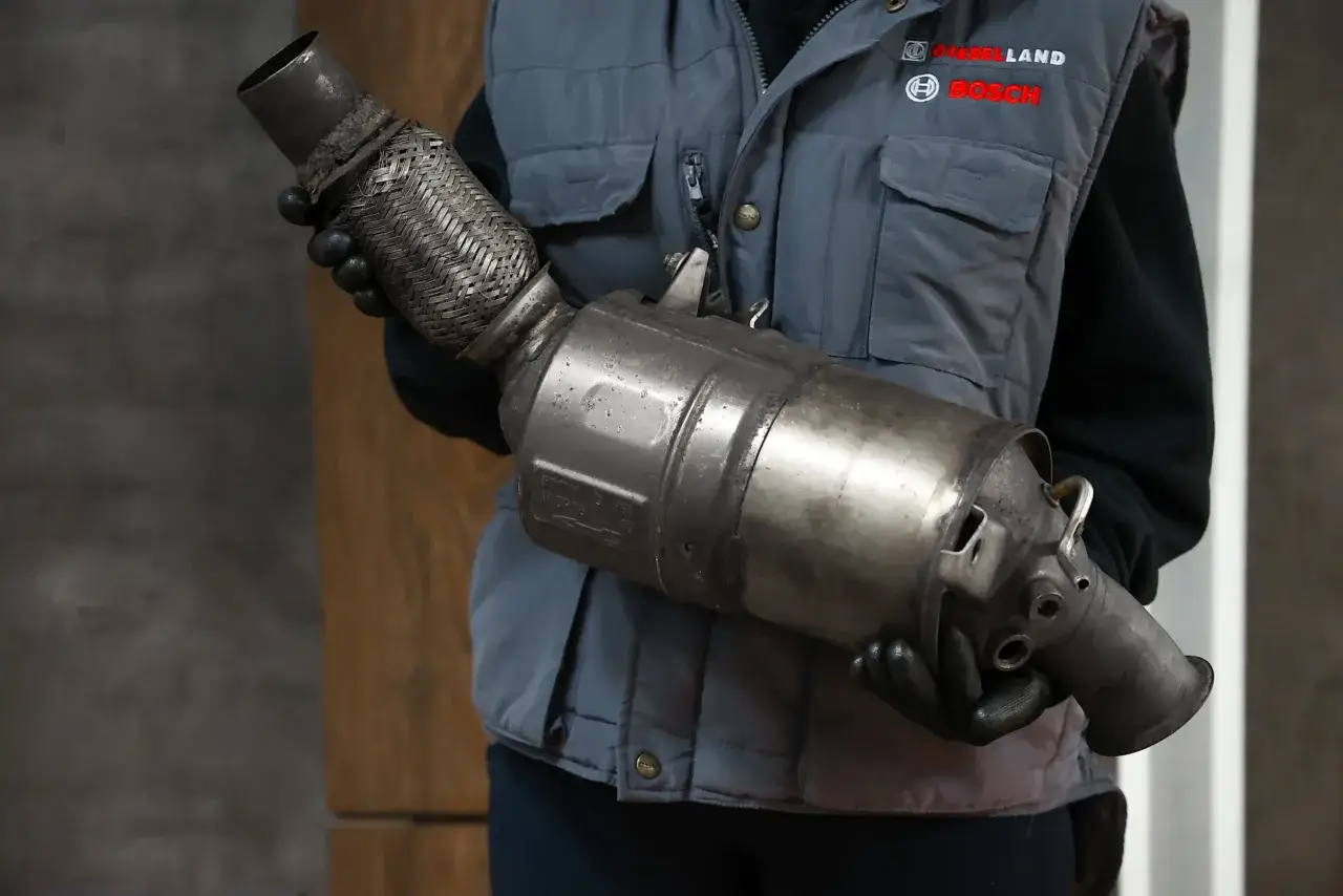 Mechanik w kamizelce z logo Bosch trzyma zużyty fap.