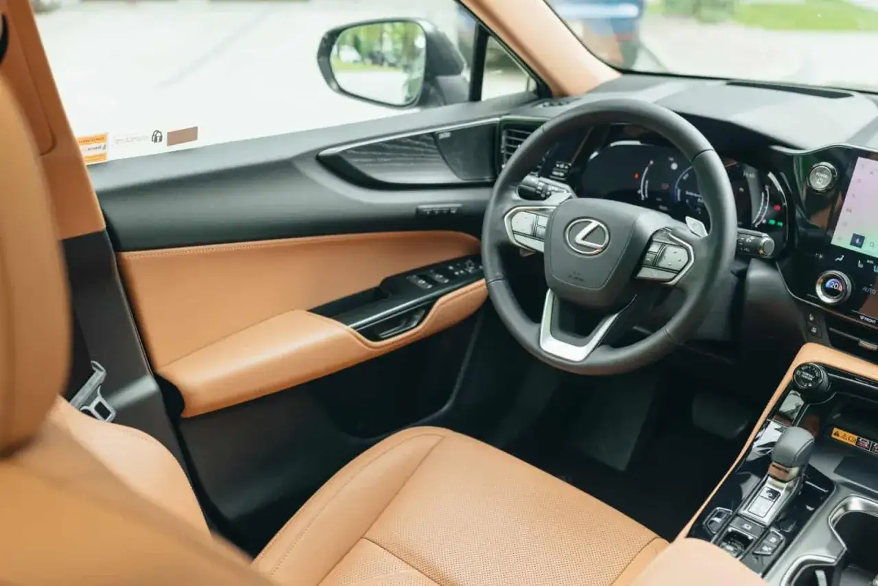 Wnętrze Lexus 350h z brązową skórzaną tapicerką, kierownicą i panelem drzwi.