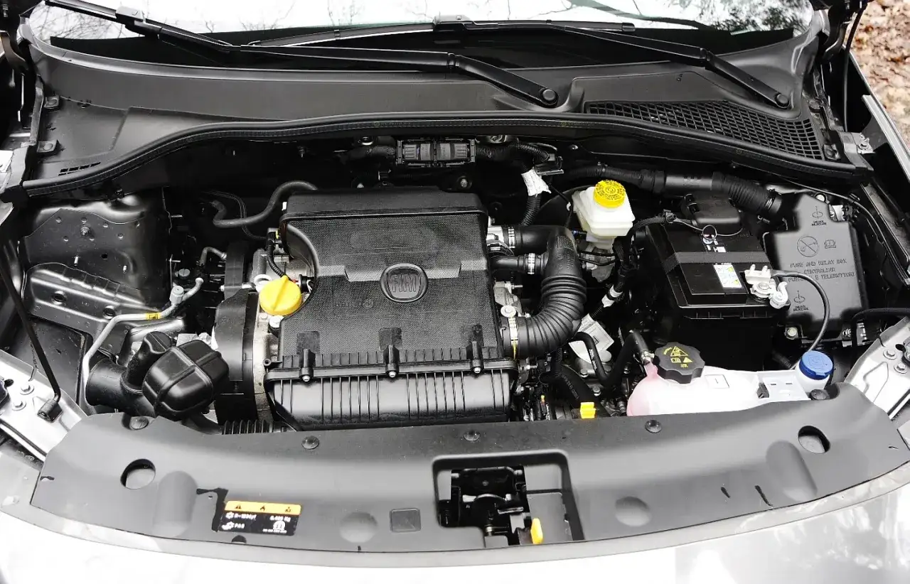 Silnik fiat tipo 1.4, czysty i zadbany, gotowy do drogi. Widać akumulator, płyny i elementy układu dolotowego.
