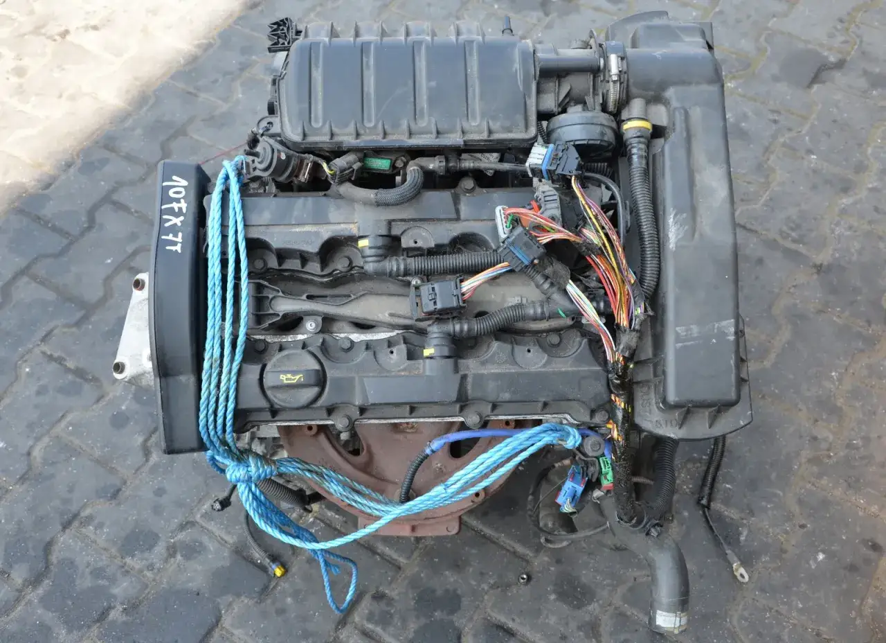 Silnik Peugeot 307 1.6 benzyna, oznaczony 107FX7T, z widocznymi przewodami i niebieską liną.