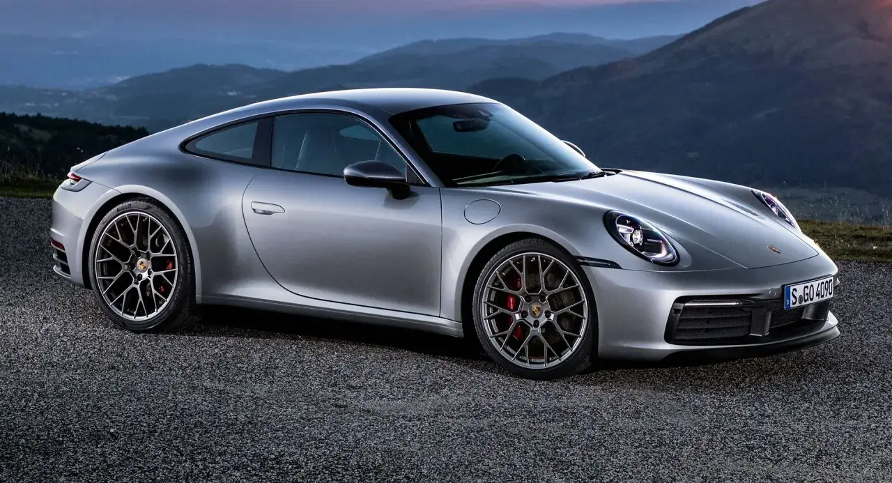 Srebrne Porsche 911 na tle gór. Zastanawiasz się, ile kosztuje Porsche 911?