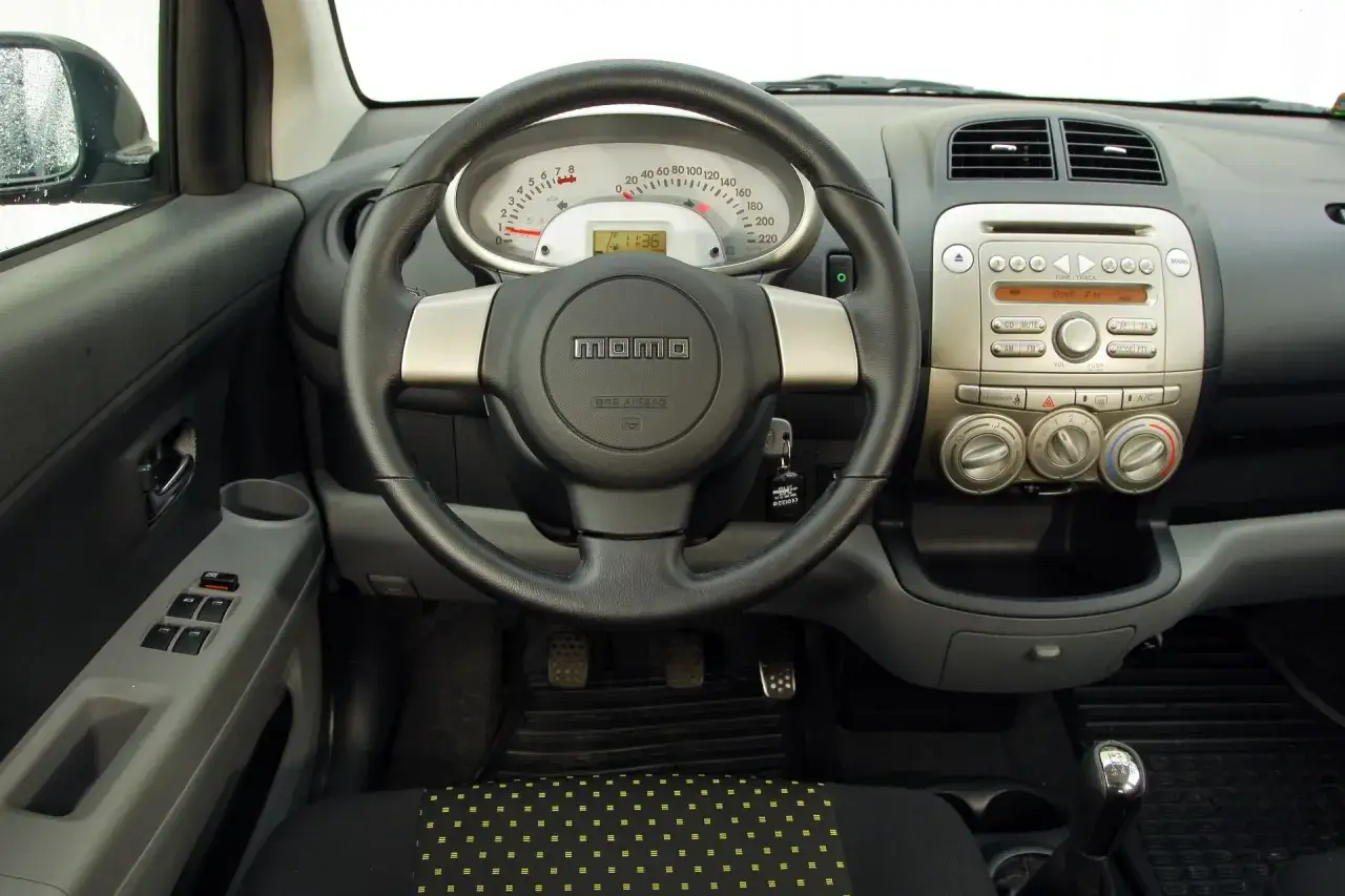 Wnętrze Daihatsu Sirion: kierownica MOMO, deska rozdzielcza z radiem i klimatyzacją, zegary.