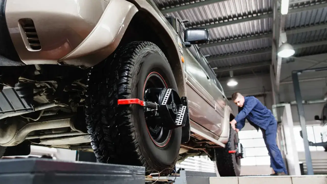Mechanik ustawia zbieżność kół w samochodzie terenowym. Dowiedz się, ile kosztuje ustawienie zbieżności.