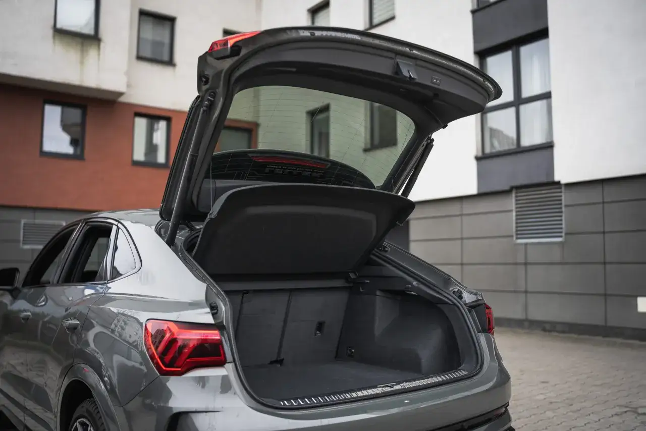 Szary Audi RSQ3 z otwartym bagażnikiem, gotowy na podróż.