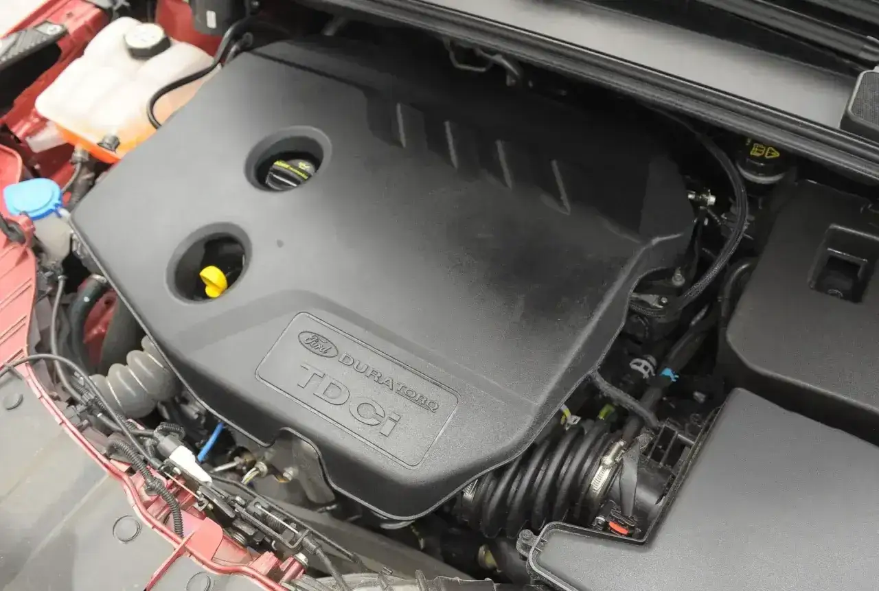 Silnik Duratorq TDCi w Fordzie Focus MK3 1.6 TDCI. Widoczna czarna osłona silnika z logo Ford.