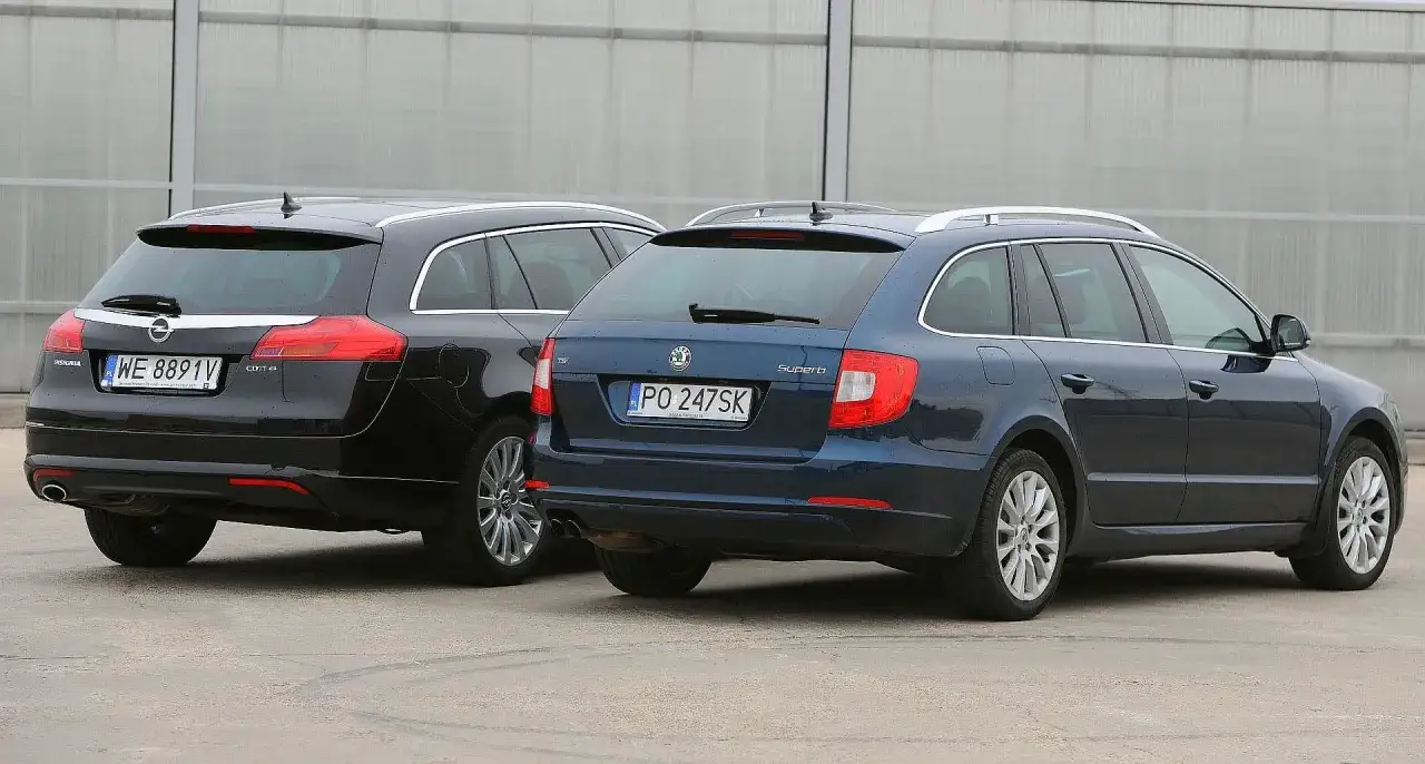 Dwa kombi, czarny Opel Insignia i granatowa Skoda Superb, stoją obok siebie.