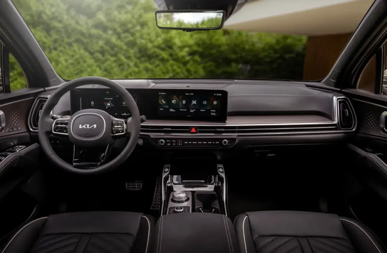 Wnętrze nowej Kia Sorento: kierownica, cyfrowe zegary, ekran multimediów i eleganckie detale.