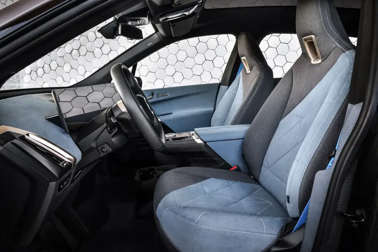 Wnętrze BMW iX z niebiesko-szarymi fotelami i nowoczesnym panelem.